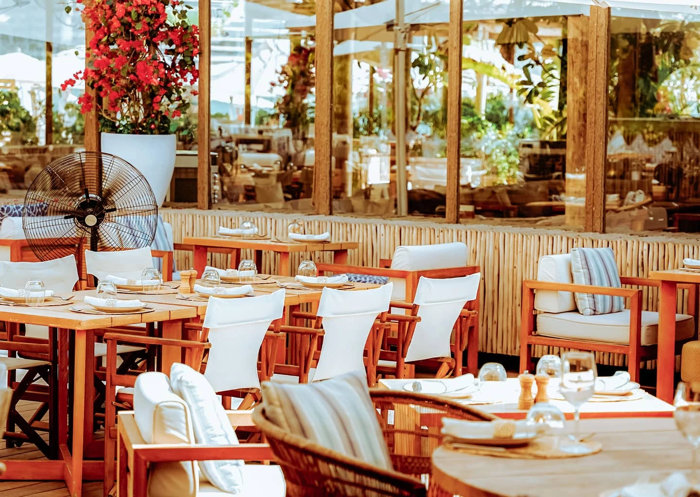 Set tables and woven chairs in Surf Club’s bright coastal-style restaurant at Palm West Beach, Dubai.