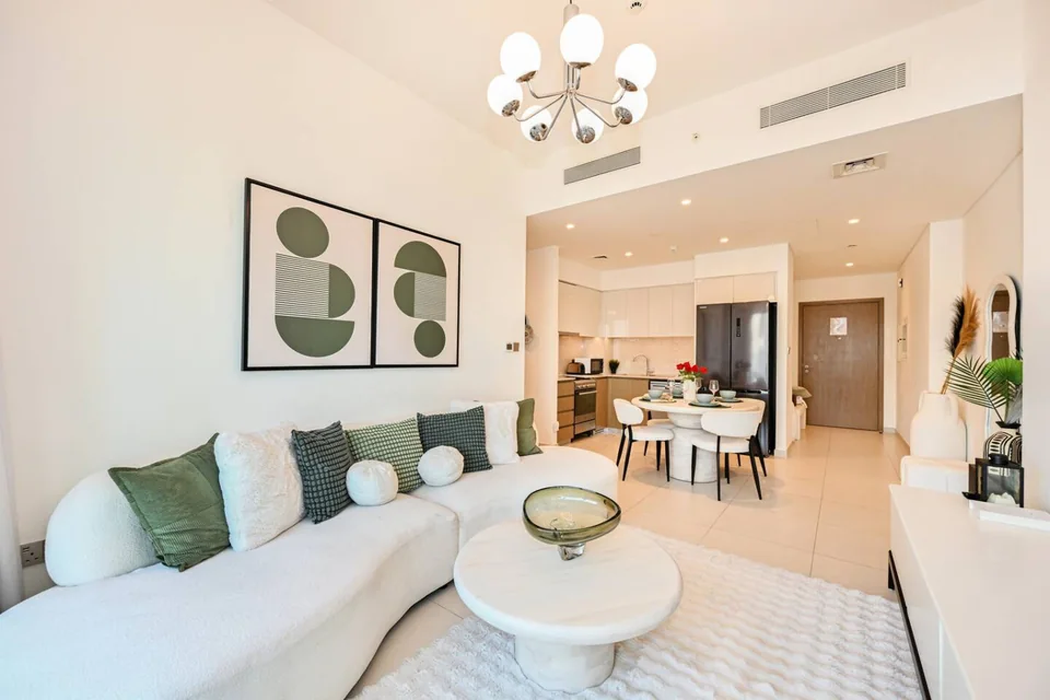 Bright living and dining room with green cushions at Burj Royale